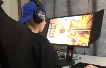 Hyrian esport-urheilija pelaa kotonaan tietokoneella työpöytänsä äärellä.