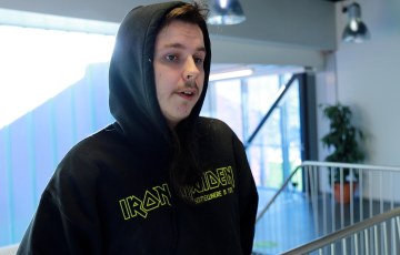 Puolivartalokuva huppariin pukeutuneesta Tommy Koskisesta nojaamassa porraskaiteeseen Sakonkadun toimipisteen aulassa