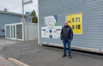 Mies seisomassa puurakennuksen edessä kadulla.