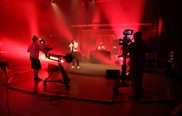 Studiossa esiintyvä artisti sekä kameramiehiä / -naisia. 
