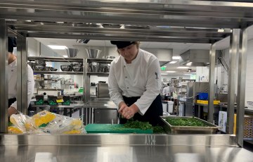 Kokkiopiskelija pilkkoo lehtipersiljaa opetuskeittiössä