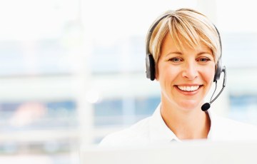 Asiakaspalveluhenkilö headset-päässään tietokoneen ruutu edessään