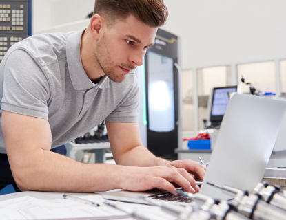 Mies näpyttelee tietokonetta kone- ja metallialan yrityksen konesalissa