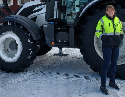 Nainen seisoo traktorin edessä talvella