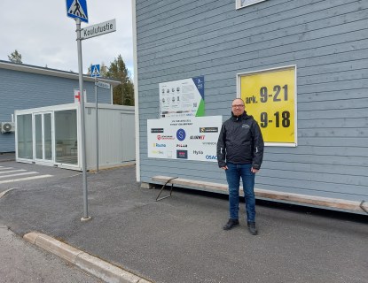 Mies seisomassa puurakennuksen edessä kadulla.