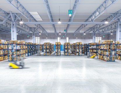 Valokuva suuresta varastosta, jossa on kaksi liikkuvaa trukkia. 