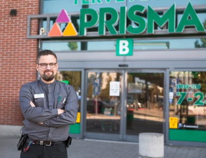 Valokuvassa on Prisman myymäläpäällikkö Anssi Vilen. Anssi seisoo Prisman edessä ja hymyilee. Hänellä on päällään Prisman työasu. 