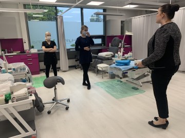 Kolme naista keskustelee kauneudenhoitoalan opiskelijoiden työsalissa.