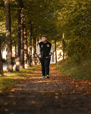 Valokuva, jossa jutussa esiintyvä Veikko kävelee syysmaisemassa kävelytiellä. Kädessä hänellä on kamera.